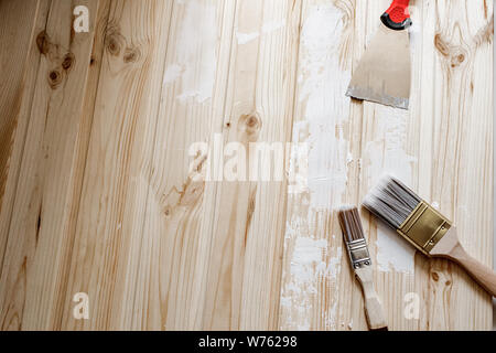 top view of a builder with a brush and spatula for applying putty on wood. It is a process with a spatula. Free space for advertising, text. Stock Photo