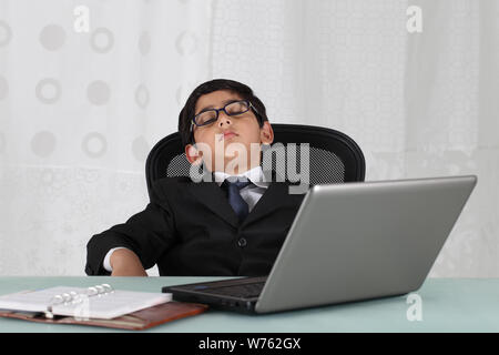 Boy pretending to be a businessman sleeping in an office Stock Photo