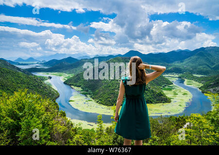 Montenegro, Pretty young woman with long hair standing at crnojevica river water bend, pavlova strana above green valley in national park skadar lake Stock Photo