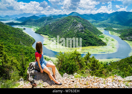 Montenegro, Stunning young blonde woman with long hair sitting on a rock at crnojevica river water bend in green canyon national park skadar lake natu