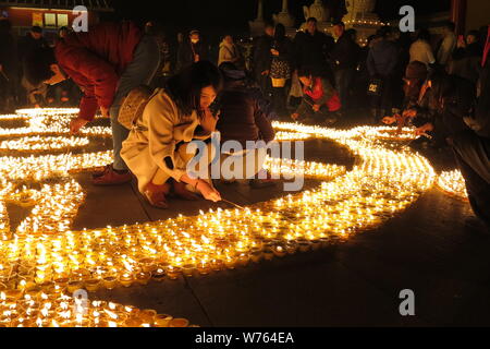 Chinese worshippers light butter lamps to pray for good fortune during a memorial festival of Tsong Khapa's death at the Guangren Lama Temple in Xi'an Stock Photo