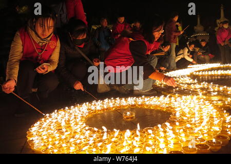 Chinese worshippers light butter lamps to pray for good fortune during a memorial festival of Tsong Khapa's death at the Guangren Lama Temple in Xi'an Stock Photo