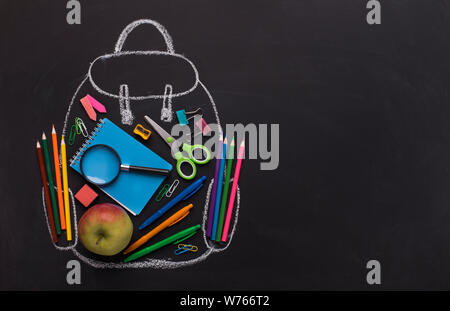 Modern backpack with school stationery inside on black board Stock Photo