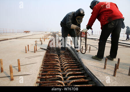 Chinese workers pave the bridge deck of the world's longest cable-stayed bridge, the Hutong (Shanghai-Nantong) Yangtze River Bridge, on the Yangtze Ri Stock Photo