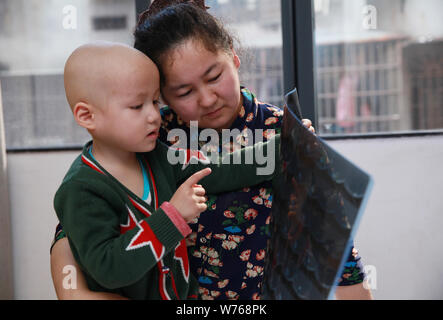 Three-year-old Uyghur boy diagnosed with rhabdomyosarcoma hugs his mother in Guangzhou city, south China's Guangdong province, 2 December 2017.   Thre Stock Photo