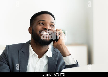 Glad african businessman talking on cellphone at office Stock Photo