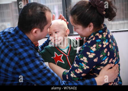 Three-year-old Uyghur boy diagnosed with rhabdomyosarcoma hugs his parents in Guangzhou city, south China's Guangdong province, 2 December 2017.   Thr Stock Photo