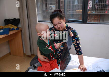 Three-year-old Uyghur boy diagnosed with rhabdomyosarcoma hugs his mother in Guangzhou city, south China's Guangdong province, 2 December 2017.   Thre Stock Photo