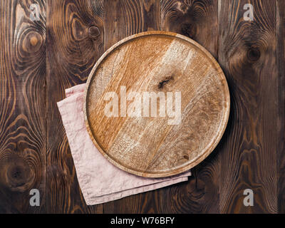 Empty wooden plate and textile napkin over brown wooden table. Top view or flat lay. Mock up for design, menu, food delivery. Copy space for text Stock Photo