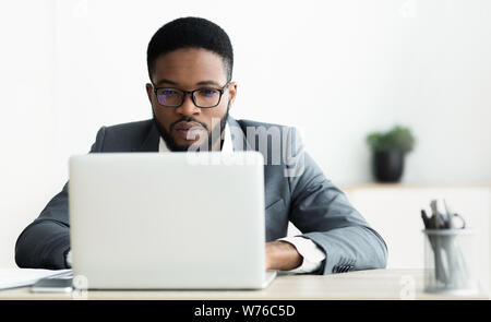 Concentrated african american guy working on laptop in office Stock Photo