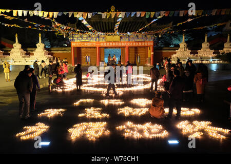 Chinese worshippers light butter lamps to pray for good fortune during a memorial festival of Tsong Khapa's death at the Guangren Lama Temple in Xi'an Stock Photo