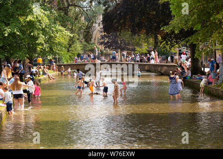 Visitors to the village of Bourton On The Water in the Cotswolds cool off in the River Windrush on the hottest day of the year. Stock Photo