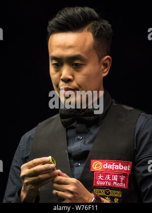 Marco Fu of Hong Kong chalks his cue as he considers a shot to Zhou Yuelong of China in their third round match during the 2017 Dafabet Scottish Open Stock Photo