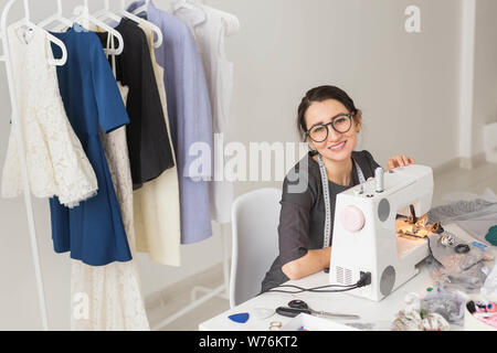 People, tailor and fashion concept - High angle view portrait of smiling fashion designer in glasses sitting at a table Stock Photo