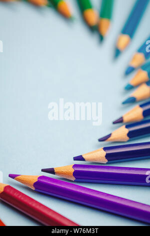 Purple, blue and green pencils laid out in a semicircle with space for text Stock Photo