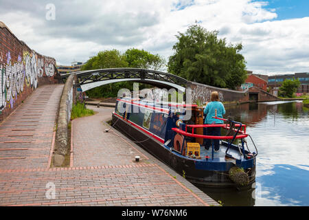 A beautiful Narrowboat, The Lily May, waits at Aston Top Lock No ! and then proceeds through and out of the lock, A woman takes the Helm whilst a man operates the Lock, Aston Birmingham, UK Stock Photo