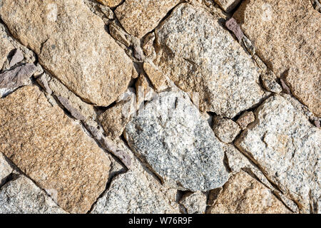 Detail of an old stone wall arranged in an irregular manner. Architecture constructions. Vintage background. Oblique lines. Stock Photo