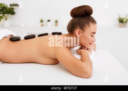Relaxed woman enjoying hot stone massage in spa Stock Photo