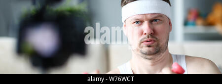 Serious Vlogger Doing Exercise with Dumbbells Stock Photo