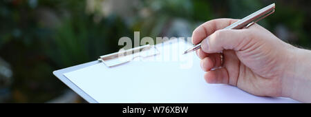 Human Hand Writing on Clipboard with White Paper Stock Photo