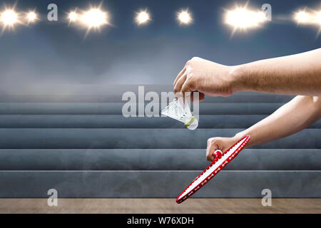 Man with badminton racket holding shuttlecock and ready in serve position on the indoor court Stock Photo