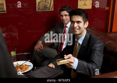 Business executives paying bill by credit card in a restaurant Stock Photo