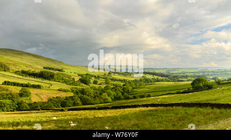 Long-distance picturesque evening view to Wharfedale (rolling clouds & hills, green pasture, sunlit valley) - Beamsley, Yorkshire Dales, England, UK.