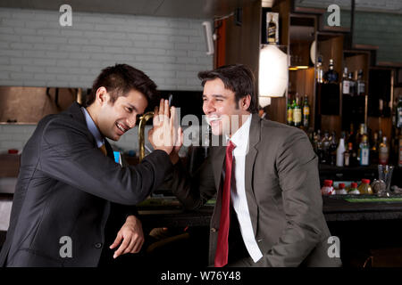 Indian business executives enjoying in a bar and giving high-five Stock Photo