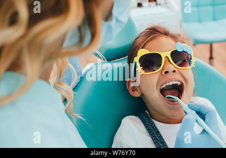 Cute little girl getting teeth exam at dental clinic Stock Photo