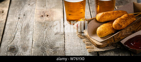Corn dogs and beer on rustic background Stock Photo