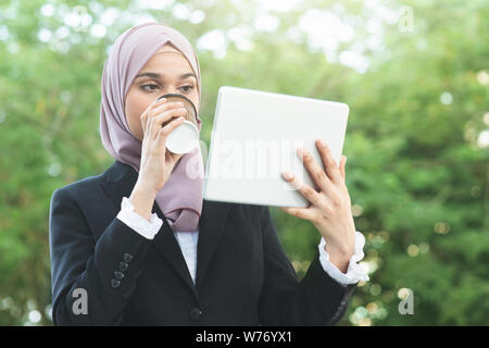 Muslim business woman drinking coffee while going to work in morning. Stock Photo