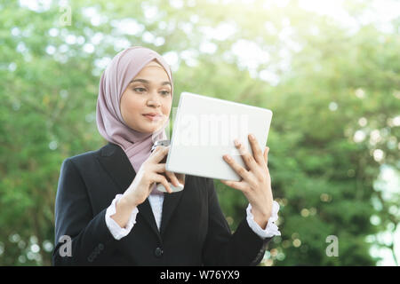 Muslim business woman drinking coffee while going to work in morning. Stock Photo