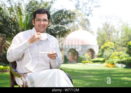 South Indian man having a cup of tea in a lawn Stock Photo