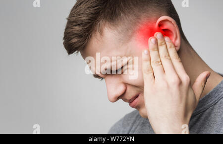 Young man has sore ear, suffering from otitis Stock Photo