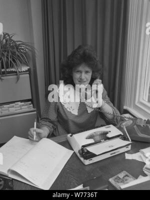 1980s, office secretary on the phone, pen in hand, with diary and typewriter of the era on her desk, England, UK. Stock Photo