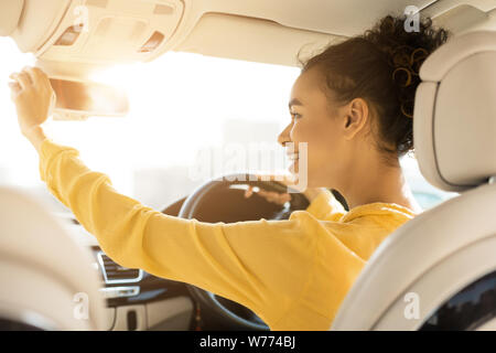 Happy girl touching rear view mirror, driving car Stock Photo