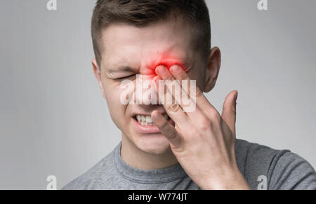 Upset man suffering from strong eye pain Stock Photo