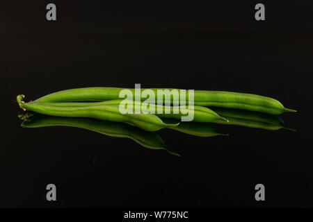 Group of three whole fresh green bean isolated on black glass Stock Photo