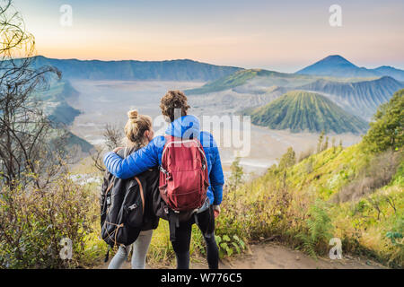 Young couple man and woman meet the sunrise at the Bromo Tengger Semeru National Park on the Java Island, Indonesia. They enjoy magnificent view on Stock Photo