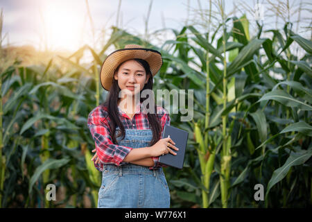 Asias women Agronomist and farmer  Using Technology for inspecting in Agricultural Corn Field Stock Photo