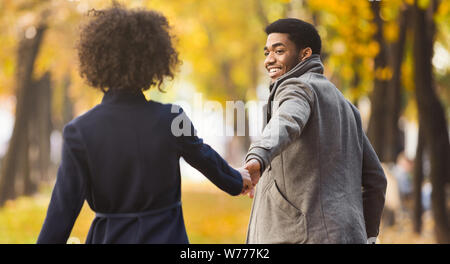 Follow me. Happy couple walking in autumn city park Stock Photo