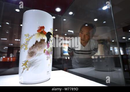(190805) -- NANCHANG, Aug. 5, 2019 (Xinhua) -- Mao Guanghui views his creation displayed at the exhibition hall of a ceramic research institute in Jingdezhen, east China's Jiangxi Province, Aug. 2, 2019. Mao Guanghui, a 56-year-old senior master of arts and crafts in Jiangxi Province, has been devoting himself to porcelain painting since the age of 13. As a third-generation disciple of Deng Bishan (1874-1930), one of the 'Eight Friends of Zhushan', a group of Jingdezhen artisans widely noted for their innovations in porcelain painting, Mao inherited not only the skills but also the art of crea Stock Photo