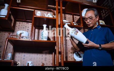(190805) -- NANCHANG, Aug. 5, 2019 (Xinhua) -- Mao Guanghui checks a piece of painted porcelain at his studio in Jingdezhen, east China's Jiangxi Province, Aug. 1, 2019. Mao Guanghui, a 56-year-old senior master of arts and crafts in Jiangxi Province, has been devoting himself to porcelain painting since the age of 13. As a third-generation disciple of Deng Bishan (1874-1930), one of the 'Eight Friends of Zhushan', a group of Jingdezhen artisans widely noted for their innovations in porcelain painting, Mao inherited not only the skills but also the art of creating porcelain painting pieces. Stock Photo