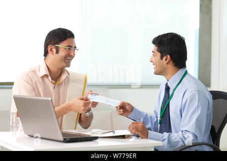 Bank manager giving cheque to his customer as loan Stock Photo