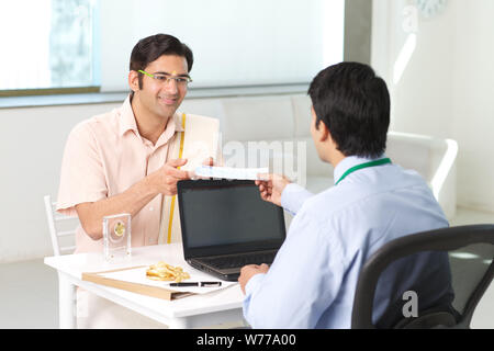 Bank manager giving cheque to his customer as loan Stock Photo