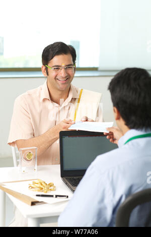 Bank manager giving cheque to his customer as loan Stock Photo