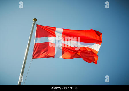 Denmark national flag waving on a blue sunny sky. Stock Photo