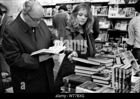 1970s busy crowded book shop people shopping browsing, teenage girl buying deciding on which book to buy. 70S UK HOMER SYKES Stock Photo