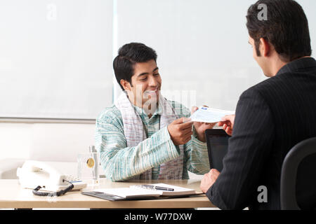Bank manager giving cheque to his customer as loan Stock Photo