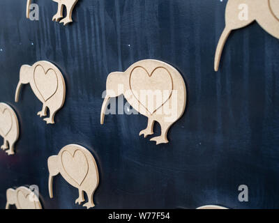 Artwork in Christchurch, New Zealand, the symbol of the Kiwi bird with heart symbols on them, made from wood on a black background Stock Photo